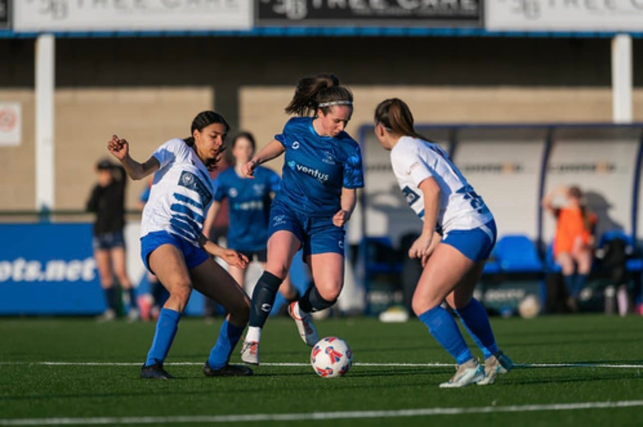 OUAFC Women's Blues player dribbling between two opponents